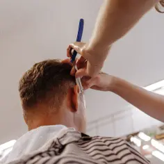 Stylista precyzyjnie modeluje fryzurę undercut damską, używając brzytwy do wykończenia detali.